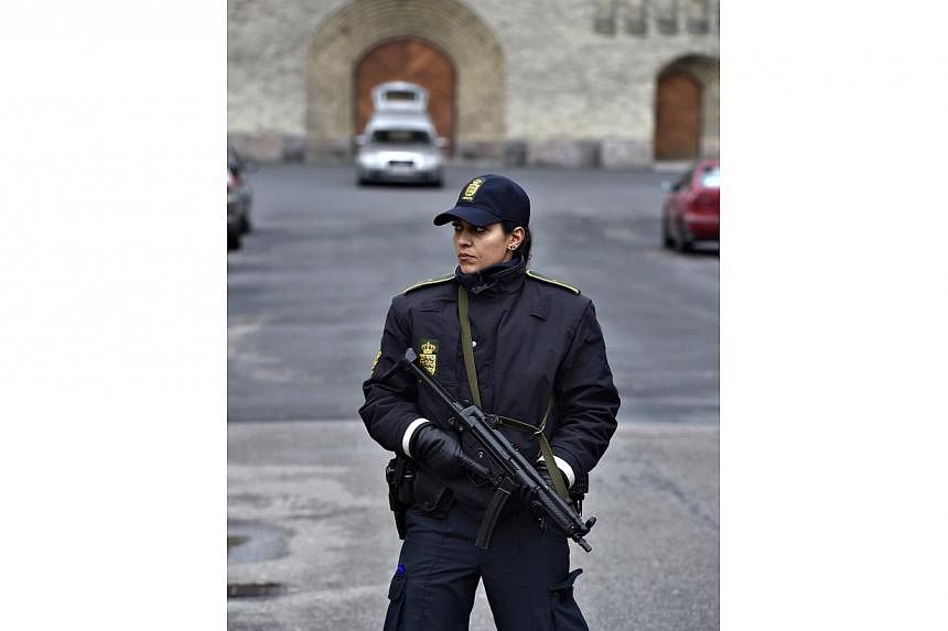 An armed female police officer standing in front of Grundtvigs Kirke (church) in Copenhagen on Feb 24, 2015 where the funeral service for Finn Noergaard is being held.&nbsp;Over 1,000 mourners turned out for the funeral. -- PHOTO: EPA&nbsp;