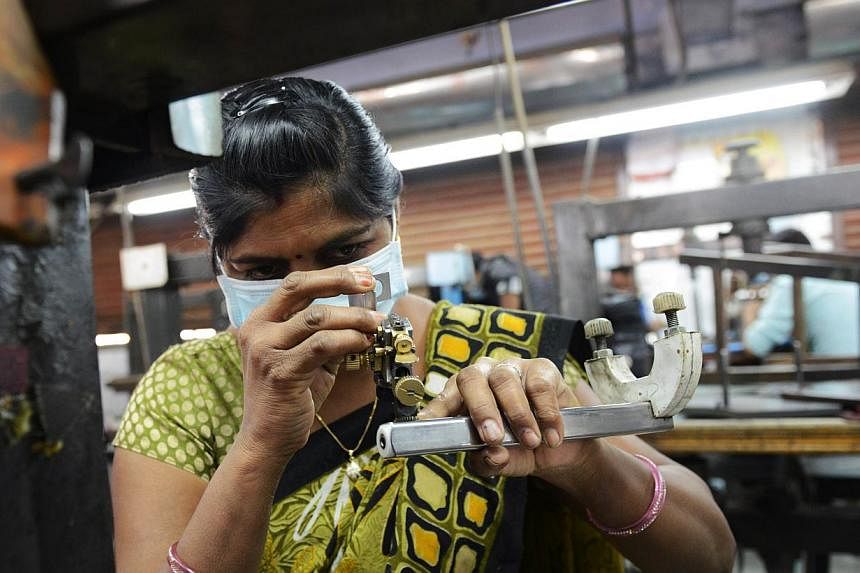 An Indian worker wears a protective mask following an outbreak of swine flu as she works at a diamond polishing factory in the Bapunagar area of Ahmedabad on Feb 20, 2015.&nbsp;An Indian city has banned public gatherings to contain the spread of dead