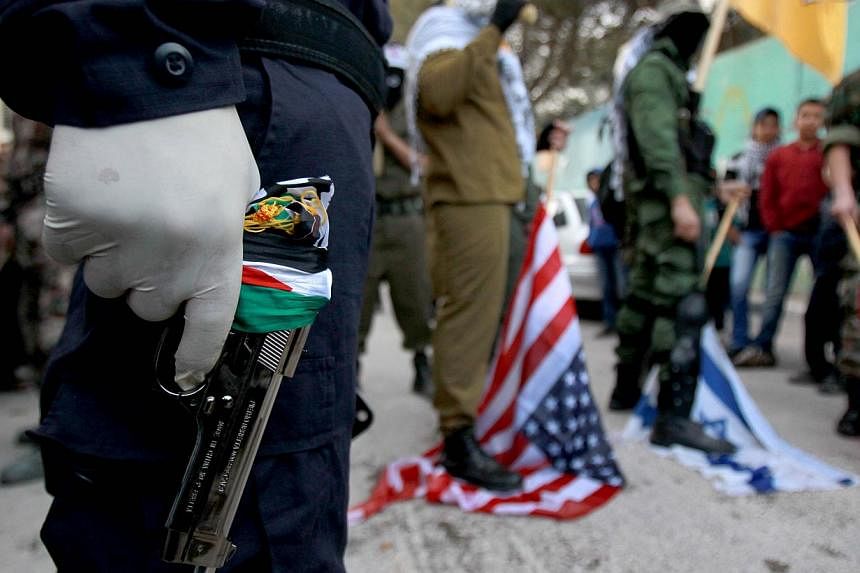 A member of the al-Aqsa Martyrs Brigades, the Palestinian Fatah movement's armed wing, carries a gun as he takes part in a rally marking the 50th anniversary of the movement's creation on January 2, 2015, in the Aida refugee camp, near the West Bank 