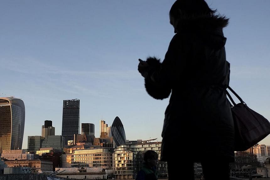 &nbsp;A pedestrian uses a smartphone as she walks near skyscrapers including left to right, 20 Fenchurch Street, also known as the "Walkie-Talkie," left, Tower 42, the Leadenhall building, also known as the "Cheesegrater," the Heron Tower, and 30 St 