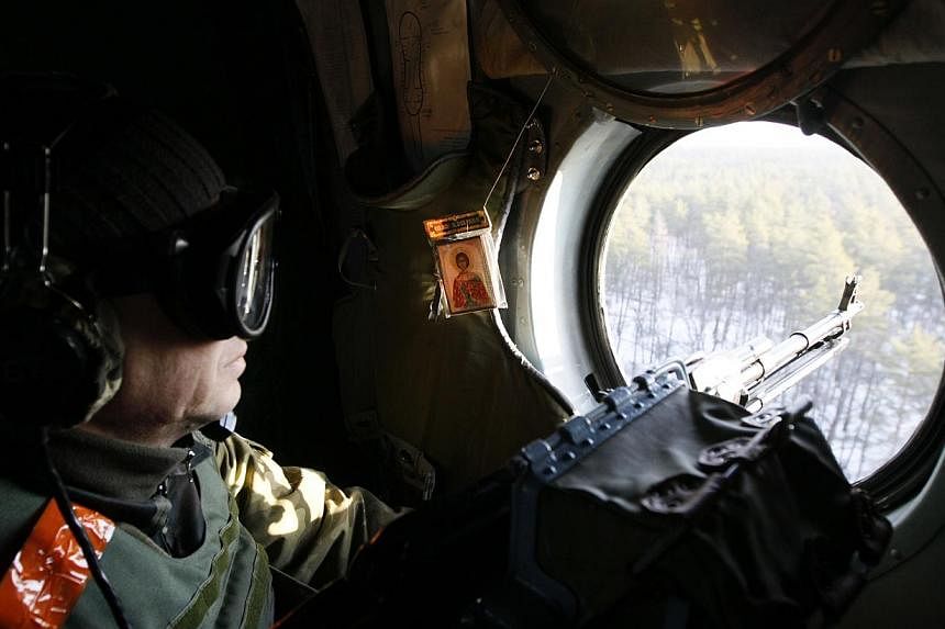 A member of the Ukrainian armed forces keeps his weapon at the ready as he looks out of a helicopter while flying above Kharkiv region on Tuesday. -- PHOTO: REUTERS