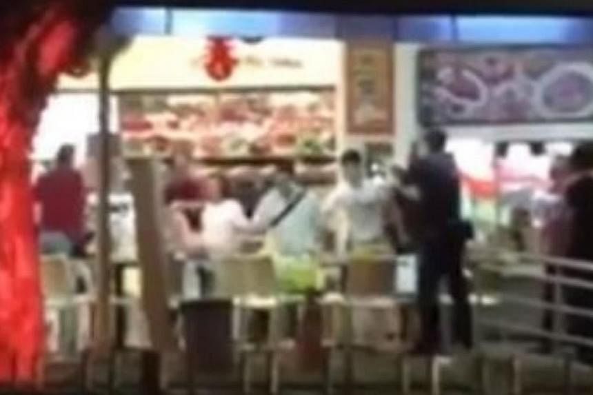 Police officers confronting the 54-year-old man (in red, far left) who was wielding a parang at a Toa Payoh Central coffeeshop on Monday night. -- PHOTO: SCREENGRAB FROM STOMP VIDEO