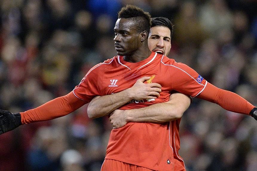 Liverpool's Italian striker Mario Balotelli (front) spreads his arms wide after scoring from the penalty spot for the opening goal as German midfielder Emre Can (back) embraces him from behind during the Uefa Europa League round of 32 first leg footb