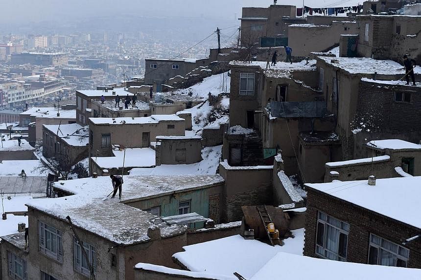 Afghan residents remove snow from the roof of houses overlooking Kabul on Jan 25, 2015. Avalanches triggered by heavy snow have killed more than 100 people in mountainous areas of northern Afghanistan, officials said on Wednesday, as rescuers battled