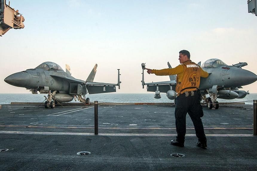 An avaiation handler signals to raise an aircraft elevator from the hangar bay to the flight deck of the aircraft carrier USS Carl Vinson during operations in the Gulf region on Jan 6, 2015.&nbsp;The American public has grown more supportive of the U