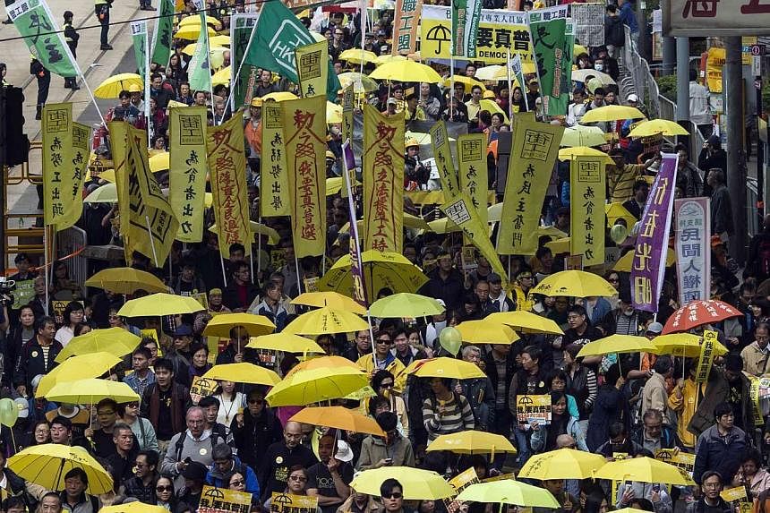 Pro-democracy protesters holding up yellow umbrellas during a march in Hong Kong on Feb 1,2015. The city's economic growth slowed in the fourth quarter as a sluggish global economy and domestic political unrest weighed on spending. -- PHOTO: REUTERS&
