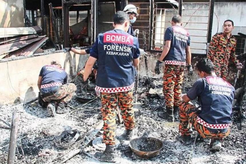 Firefighters sifting through the burnt remains of the house in Serdang. -- PHOTO: THE STAR/ASIA NEWS NETWORK