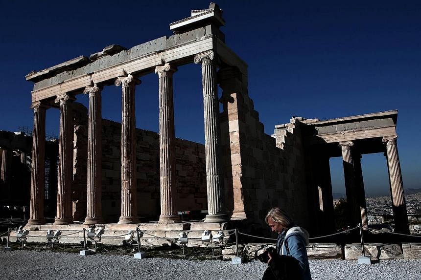 A tourist walks in front of the Erechtheion Temple at the Acropolis hill in Athens on February 21, 2015. The hard work for Greece’s new anti-austerity government began Wednesday after it secured an extension to its lifeline financial bailout with p