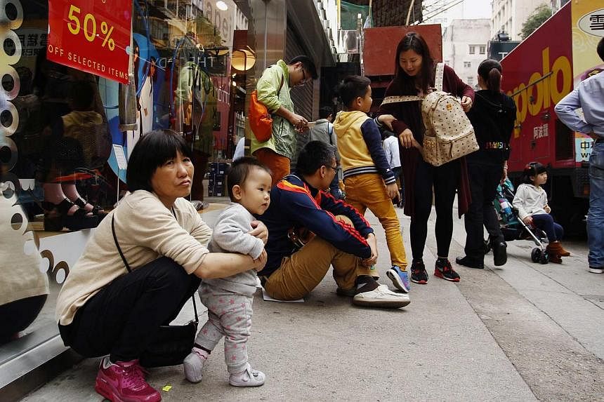 Mainland Chinese visitors resting outside a shop in Hong Kong on Feb 24, 2015. -- PHOTO: REUTERS