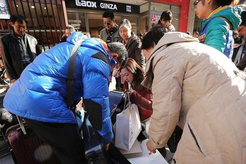Chinese tourists pack purchases into suitcases outside a store in the Ginza district of Tokyo, Japan. With tensions easing between the two countries, Tokyo is hoping to capitalise on the rising number of Chinese travelling abroad each year. -- PHOTO: