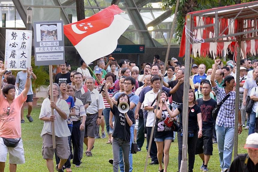 Han Hui Hui (with loudspeaker) and Roy Ngerng (carrying state flag) with supporters at the Return Our CPF rally, marching round the park at the conclusion of the rally, on Sept 27, 2014. Blogger Han Hui Hui has been given until March 25 to decide whe