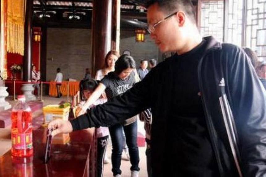 This man was photographed slipping his iPhone 6 into the donation box at a temple in Foshan, Guangdong province on Feb 22, 2015. -- PHOTO: YOUXI.YOUTH.CN &nbsp;