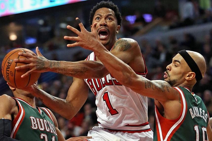 Derrick Rose (#1) of the Chicago Bulls drives between Giannis Antetokounmpo (#34) and Jerryd Bayless (#19) of the Milwaukee Bucks at the United Center on Feb 23, 2015 in Chicago, Illinois. -- PHOTO: AFP