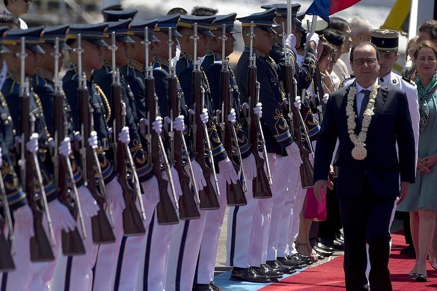 French President Francois Hollande (right) walking past a Philippine honour guard as he arrives at a military airbase in Manila on Feb 26, 2015. -- PHOTO: AFP