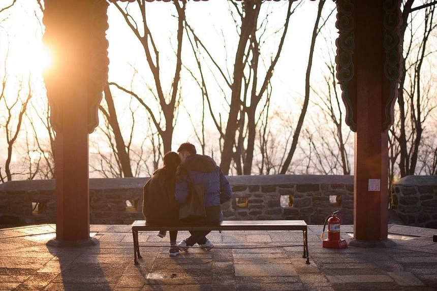 A couple kiss in a pagoda overlooking the Seoul city skyline on Feb 13, 2015. Share price of South Korea's biggest condom maker surged on Thursday, Feb 26, 2015,&nbsp;after the country's highest court struck down a decades-old law banning adultery. -
