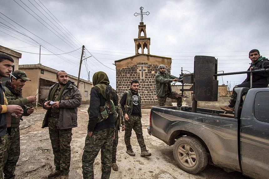 Fighters of the Kurdish People's Protection Units (YPG) stand in front of a church in the Assyrian village of Tel Jumaa, north of Tel Tamr town on&nbsp;Feb 25, 2015. Islamic State in Iraq and Syria (ISIS) militants have abducted at least 220 people f