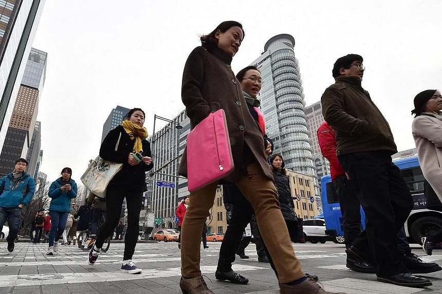 Pedestrians crossing an intersection in the business district in Seoul on Jan 14, 2015. -- PHOTO: AFP