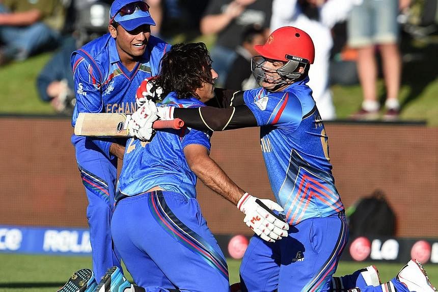 Afghanistan batsman Shapoor Zadran (centre) celebrates with teammate Hamid Hassan (right) after hitting the winning runs to defeat Scotland as reserve Usman Ghani (left) looks on in their 2015 Cricket World Cup Group A match in Dunedin on Feb 26, 201
