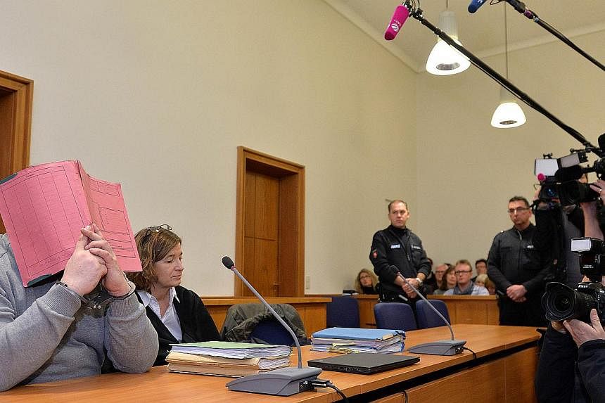 German&nbsp;hospital nurse Niels H (left) hides his face behind a folder as he waits next to his lawyer Ulrike Baumann (second, left) for the opening of another session of his trial on Feb 26, 2015, at court in Oldenburg, north-western Germany. -- PH