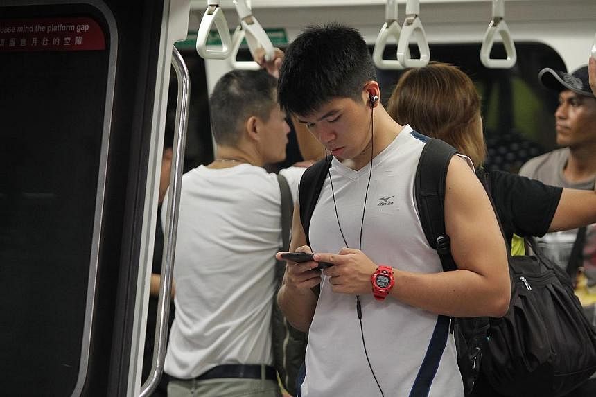 A commuter listening to music using earphones in a Singapore train on March 27 2014.&nbsp;More than one billion young people risk damaging their hearing through listening to loud music, the World Health Organisation said on Friday. -- ST FILE PHOTO