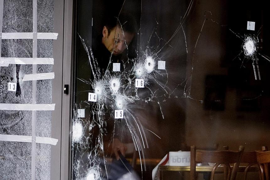 Police forensics inspect bullet holes in the door of Krudttoenden cafe where the terrorist attack started in Copenhagen, Denmark, Feb 15, 2015. A third alleged accomplice was charged on Saturday. -- PHOTO: EPA