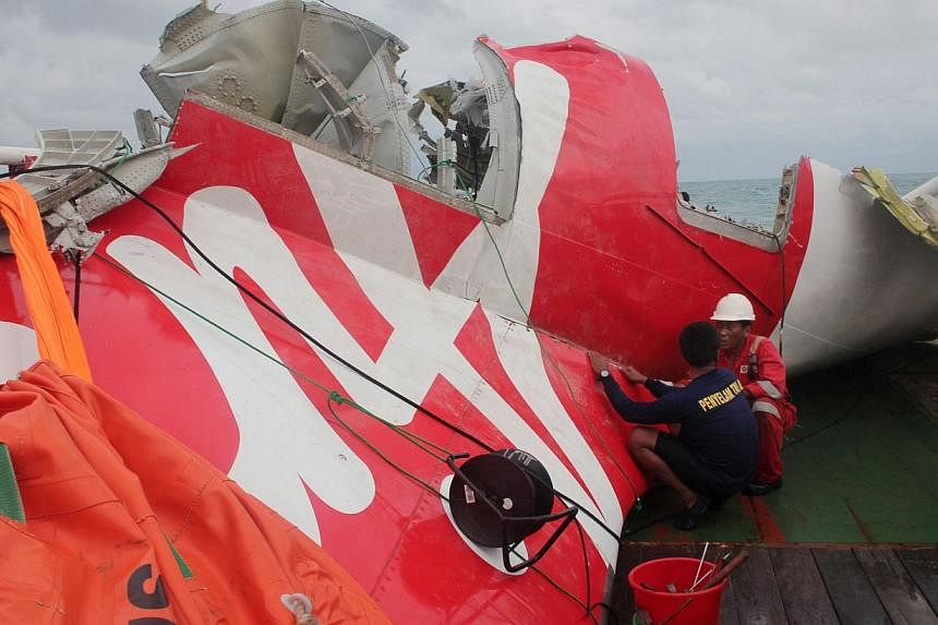 In this file photograph taken on Jan 10, 2015, an Indonesian diver and an official examine the wreckage from AirAsia flight QZ8501 after it was lifted into the Crest Onyx ship at sea.&nbsp;Indonesia has retrieved the final major part of the fuselage 