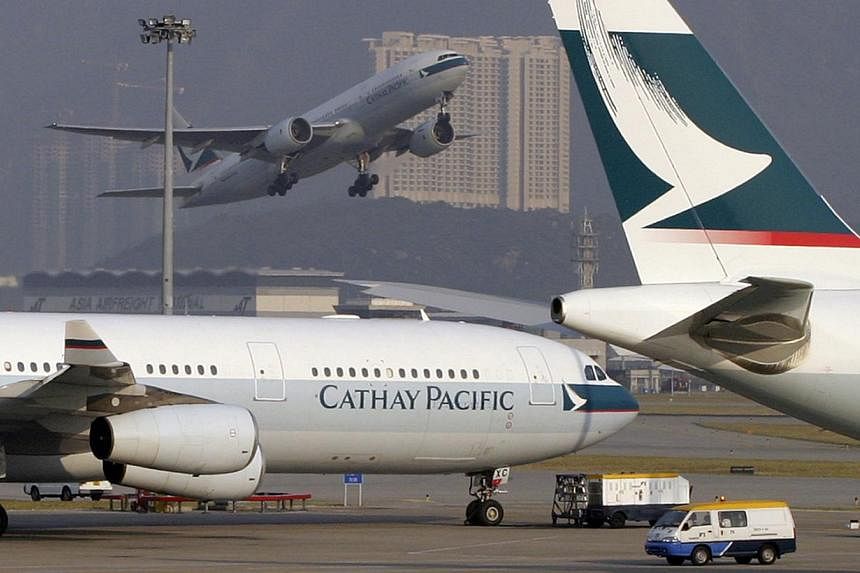 Cathay Pacific jets sit on the runway at Hong Kong's Chek Lap Kok airport on Friday, October 17, 2003 as another takes off in the background. -- FILE PHOTO: BLOOMBERG