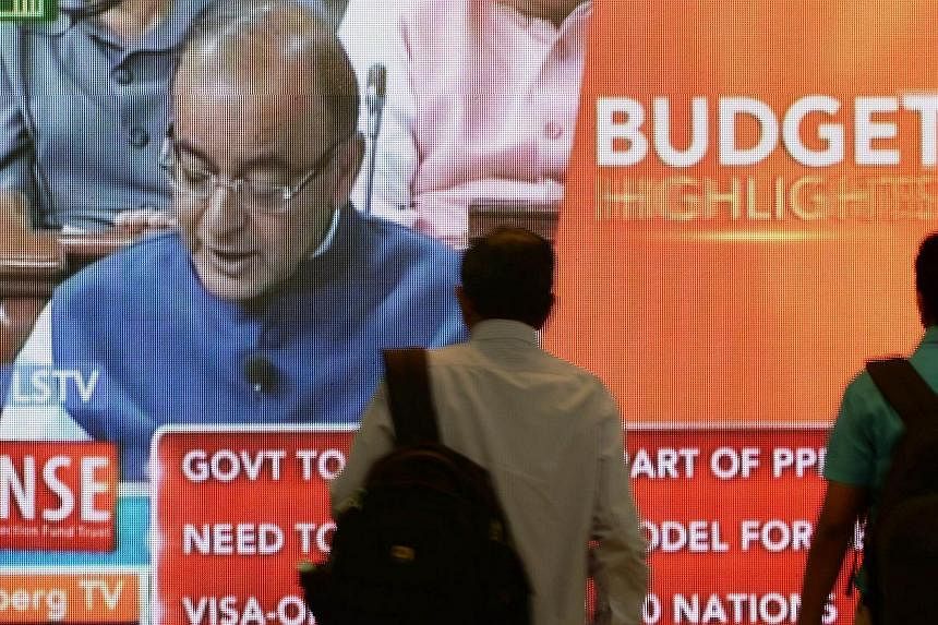Indian office workers walk past a digital screen showing Indian Finance Minister Arun Jaitley delivering his Budget speech at Parliament in New Delhi, on Feb 28, 2015.&nbsp;The Indian government's budget was praised on Sunday, Mar 1, as balancing the