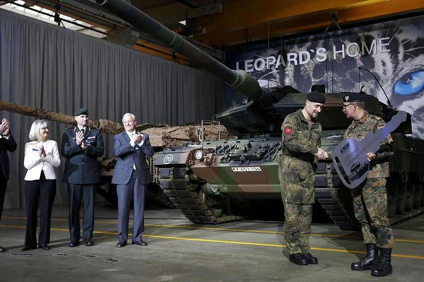 German General Rainer Korff (right) hands over a symbolic key to Master Sergeant Sascha Sieson during the handover of the new tank Leopard 2A7 from Krauss-Maffei Wegmann (KMW) to the German armed forces in Munich on Dec 10, 2014.&nbsp;Germany will sp