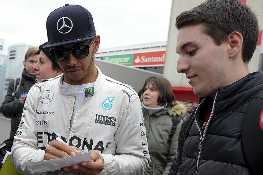 Mercedes AMG Petronas F1 Team's British driver Lewis Hamilton signs autographs during the first day of the third and last segment of Formula One pre-season tests at the Circuit de Catalunya, in Montmelo on the outskirts of Barcelona on Feb 26, 2015. 