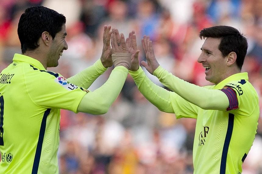 Barcelona's Argentinian forward Lionel Messi (right) celebrates a goal with teammate Luis Alberto Suarez during their match against Granada on Feb 28, 2015. -- PHOTO: AFP&nbsp;