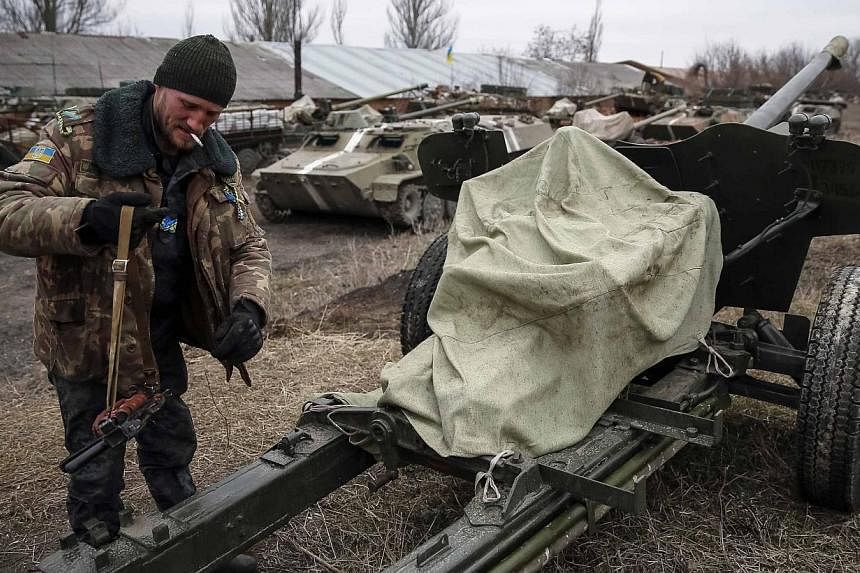 A Ukrainian serviceman stands near armoured personnel carriers, military vehicles and cannons at their new position as they pull back from the Horlivka region, near Druzhkivka, eastern Ukraine, Feb 28, 2015. -- PHOTO: REUTERS