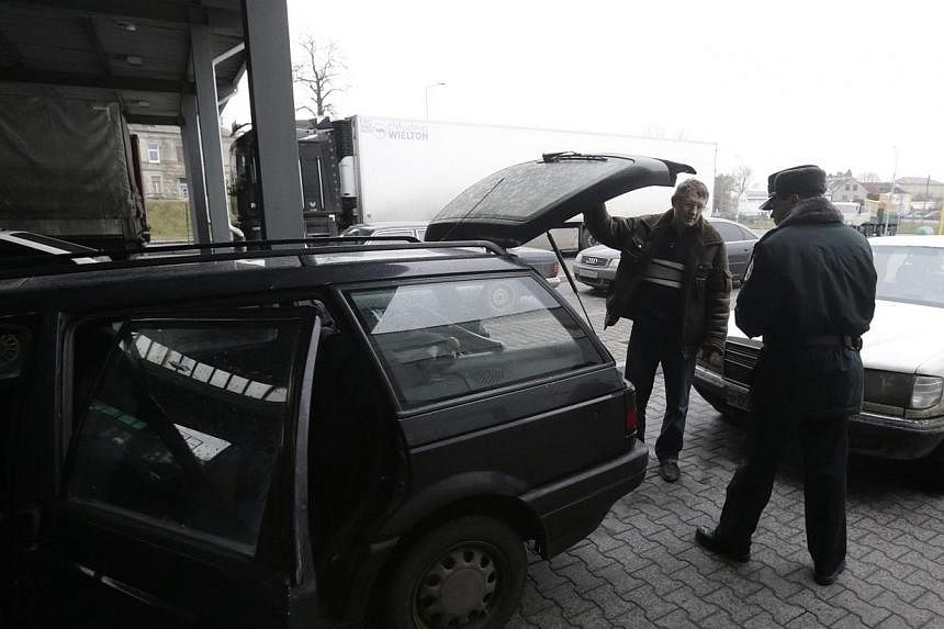 A Lithuanian border guard inspects a car as it enters Lithuania at a border crossing with Russia in Kybartai on Dec 16, 2014.&nbsp;Singapore must keep up its strong defence and can learn from Lithuania, said Defence Minister Ng Eng Hen on Sunday. -- 