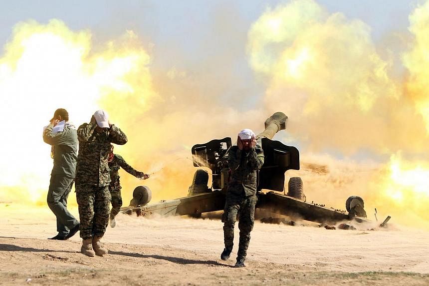 Volunteer Shiite fighters, who support the Iraqi government forces in the combat against ISIS, firing a Howitzer artillery canon in the village of Awaynat near the city of Tikrit on Feb 28, 2015.&nbsp;-- PHOTO: AFP