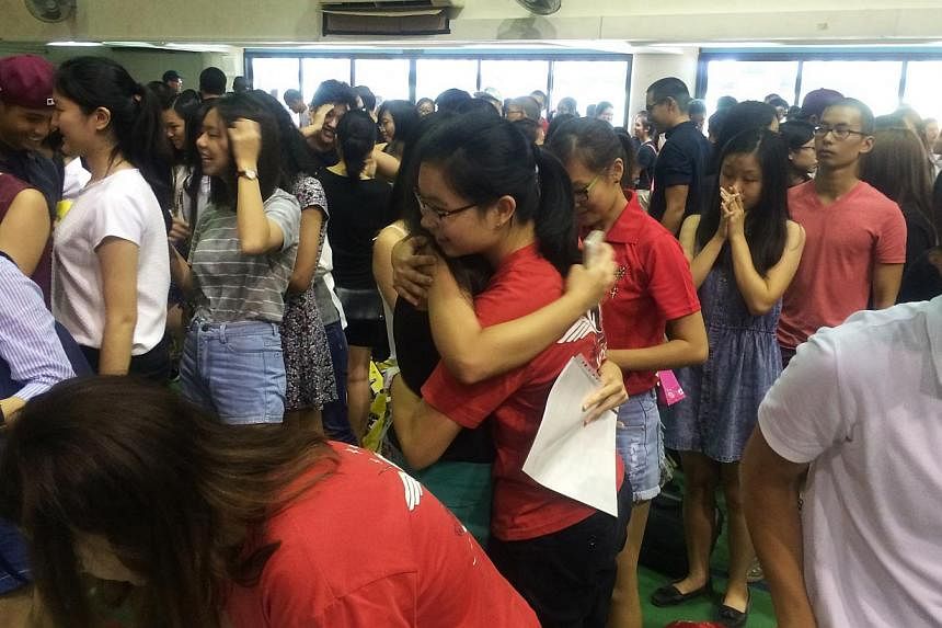Hwa Chong institution students congratulating each other after receiving their A-level results while others wait anxiously in their school hall on Monday, March 2, 2015. -- ST PHOTO: SEAH KWANG PENG