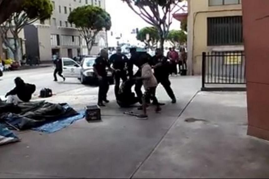 Police officers wrestling with the homeless man, whom they later fatally shot, in the background of a video posted online. -- PHOTO: SCREENGRAB FROM FACEBOOK VIDEO