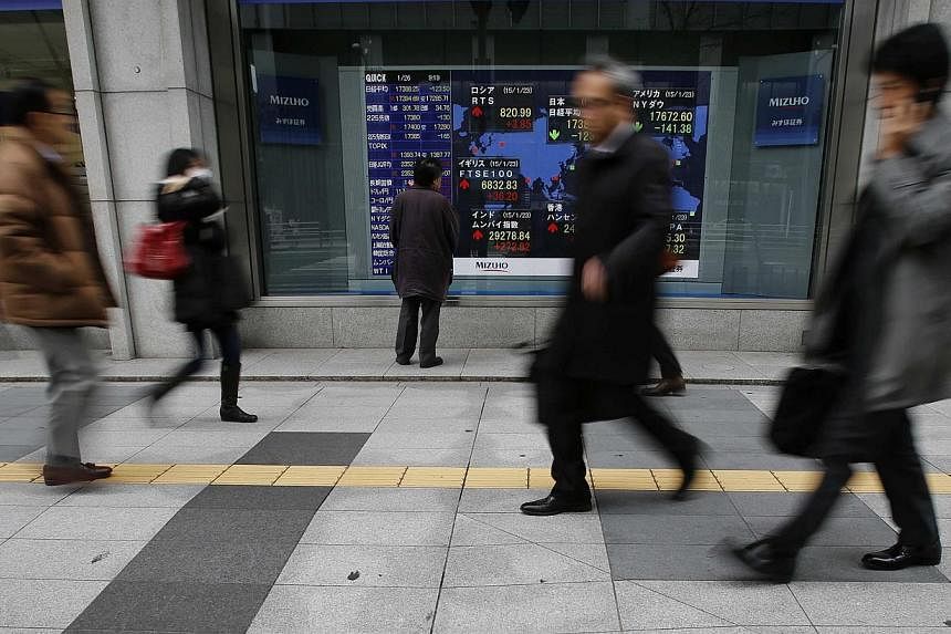 A man looking at an electronic board showing the stock market indices of various countries outside a brokerage in Tokyo on Jan 26, 2015. -- PHOTO: REUTERS