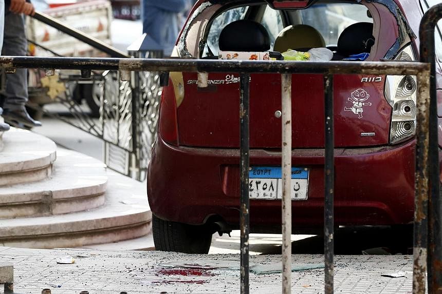 Blood stains are seen on the ground as security officials inspect the scene of a car bomb blast in front of The High Court in downtown Cairo on Monday. At least eight people were wounded, security sources said. -- PHOTO: REUTERS