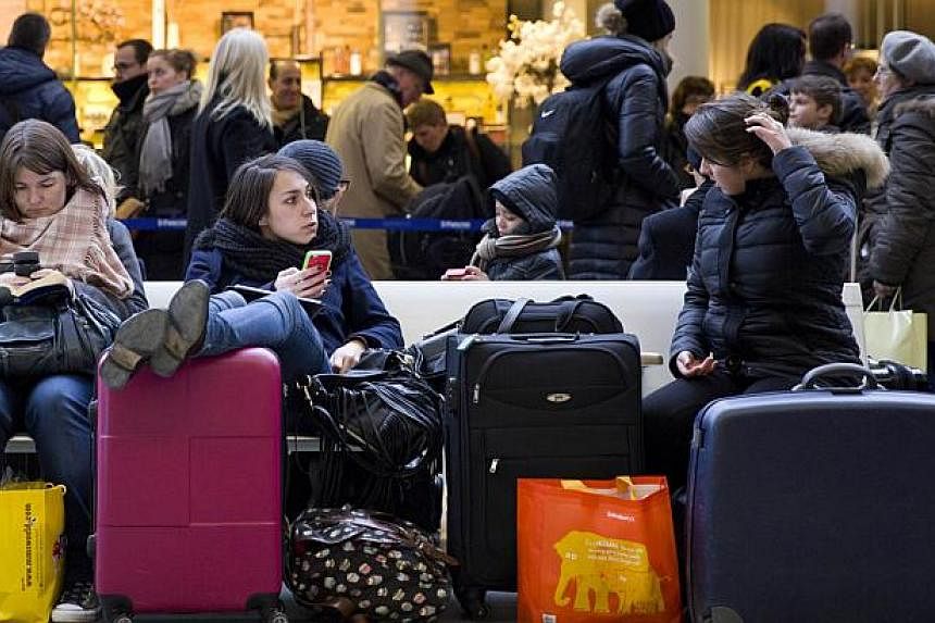 Passengers sit and wait at the Eurostar train terminal at St Pancras International station in London on Monday, after a fatality on the line in Kent. -- PHOTO: AFP