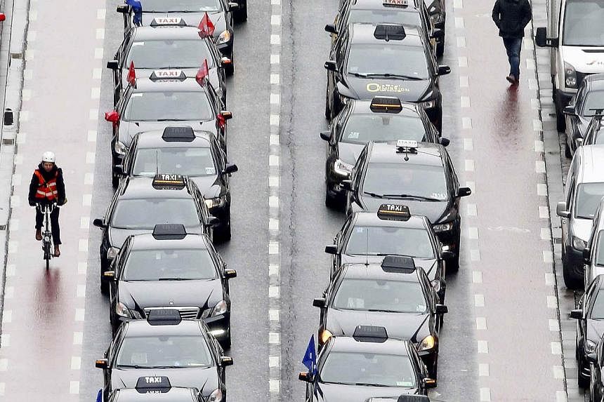 axi drivers line a street during a protest against online ride-sharing company Uber, in central Brussels on Tuesday. -- PHOTO: REUTERS