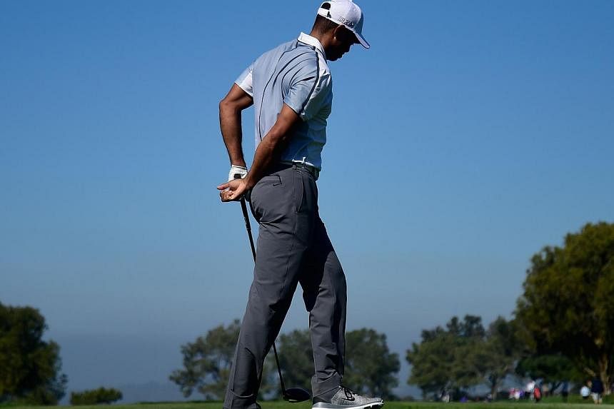 Tiger Woods holds his back after playing his tee shot on the 15th hole of the north course during the first round of the Farmers Insurance Open at Torrey Pines Golf Course on Feb 5 In La Jolla, California. -- PHOTO: AFP