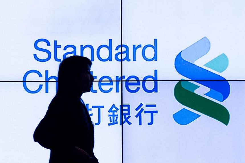 A woman walks past an electronic board displaying the logo of the Standard Chartered bank in Hong Kong on March 4, 2015.&nbsp;Standard Chartered ruled out plans to raise capital on Wednesday despite reporting a 25 per cent slide in annual pretax prof