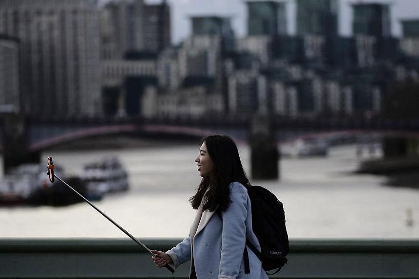 A woman taking a photo using a selfie stick. Washington's top museums say selfie sticks are banned, in a growing trend among visitor centres in the United States to outlaw the devices. -- PHOTO: REUTERS