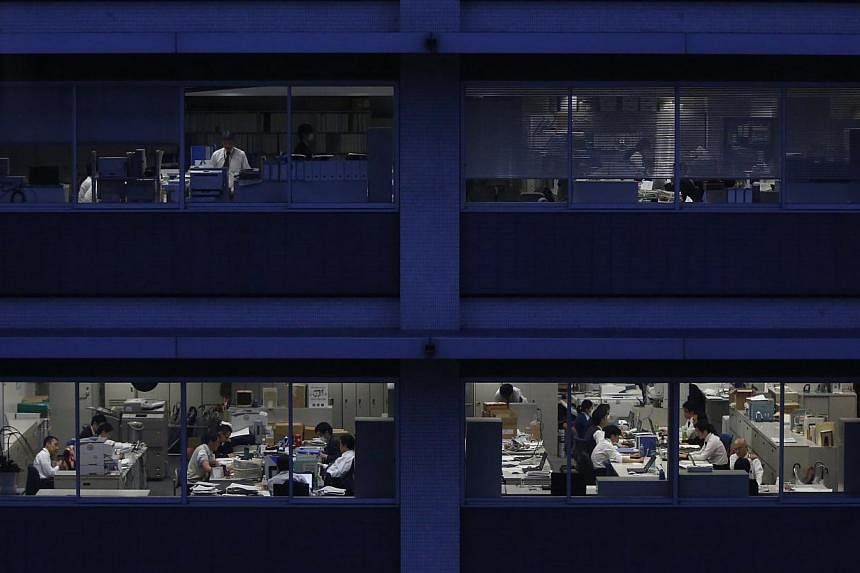 Officer workers are pictured through building windows during dusk in Tokyo on Mar 3, 2015.&nbsp;Millions of Japanese workers are taking home their smallest share of corporate income in two decades as companies build record cash hoards and abstain fro