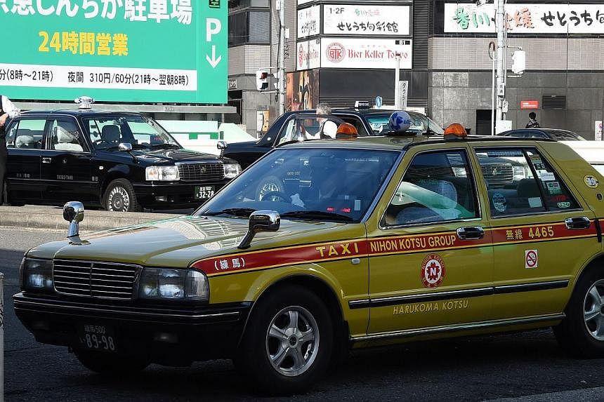 Taxi drivers wait for passengers in front of a railway station in Tokyo. Japan has slammed the brakes on a pilot project by taxi service Uber less than a month after it was launched. -- PHOTO: AFP