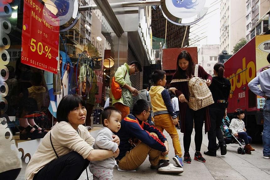 Tourists from mainland China resting outside a shop at a shopping district in Hong Kong on Feb 24, 2015. -- PHOTO: REUTERS&nbsp;