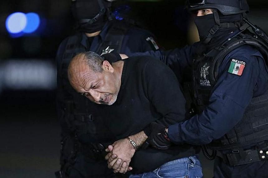 Former primary school teacher Servando "La Tuta" Gomez is escorted by police officers during a media conference about his arrest in Mexico City last week. Mexico captured its most wanted drug lord on Friday, delivering a boost to a government battere