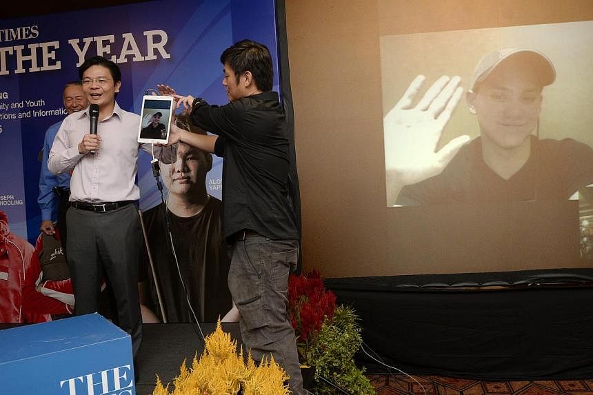 The Straits Times Athlete of the Year Joseph Schooling waves to the crowd via a Skype conversation after his father Colin (far left, partially hidden) accepted the award on his behalf from Minister for Culture, Community and Youth Lawrence Wong (in w