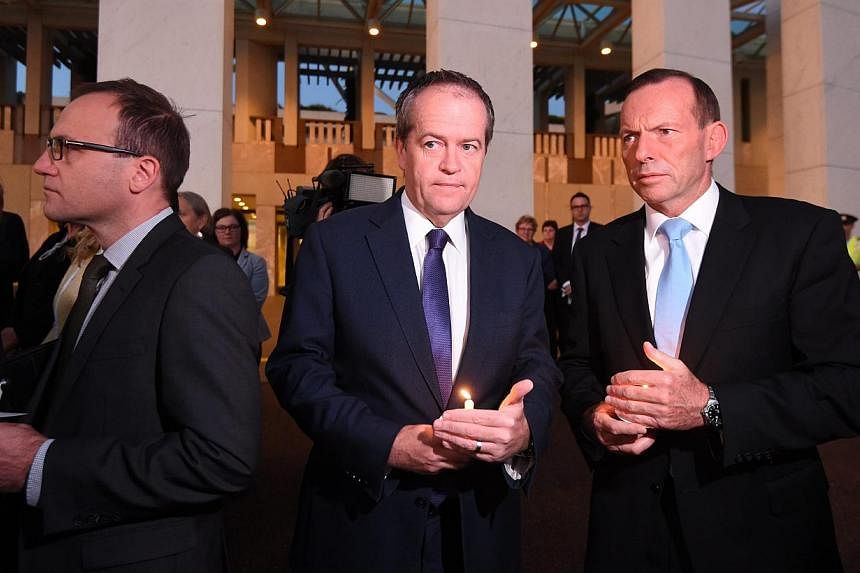 Australian opposition Leader Bill Shorten (centre) and Prime Minister Tony Abbott (right) attending a dawn candlelight vigil at Parliament House in Canberra on March 5, 2015. The vigil was held for Bali Nine ringleaders Myuran Sukumaran and Andrew Ch