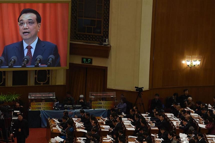 Delegates listening as Chinese premier Li Keqiang (on screen) delivers his work report during the 12th National People's Congress in Beijing on March 5, 2015. -- PHOTO: AFP